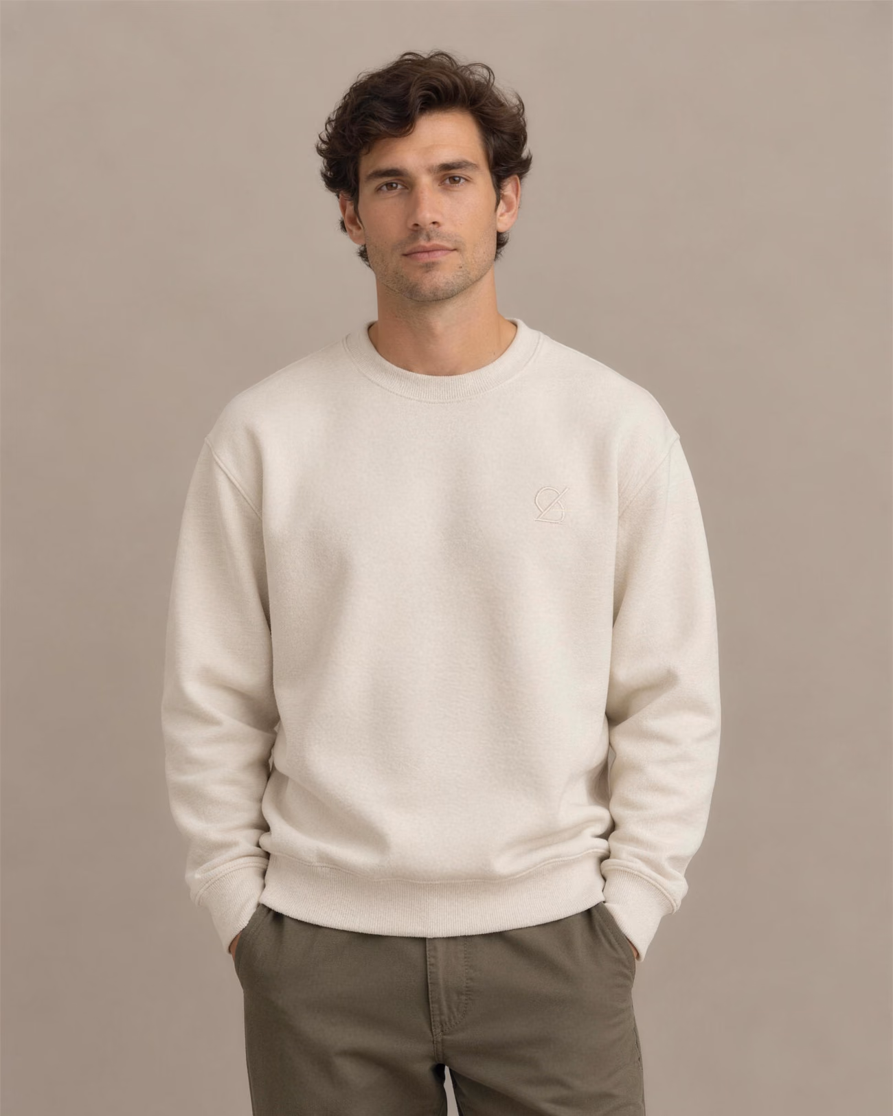 Wide shot: Cream sweatshirt with a tone-on-tone embroidered emblem on the chest